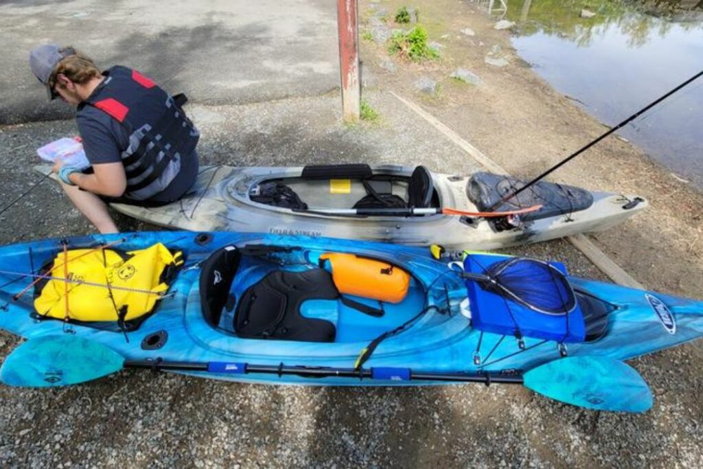 un kayakiste ajuste son équipement avant une sortie en kayak sit in (cockpit fermé) sur un grand plan d'eau