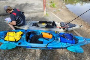 un kayakiste ajuste son équipement avant une sortie en kayak sit in (cockpit fermé) sur un grand plan d'eau