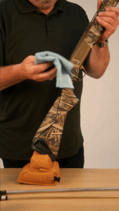 Cleaning the stock of a hunting rifle with a soft cloth.