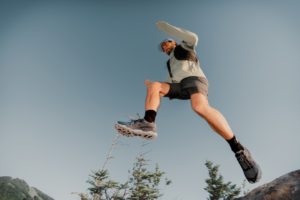 man leaping across rocky terrain in trail running shoes