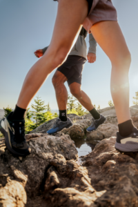 close-up of two people wearing trail running shoes on rocky terrain