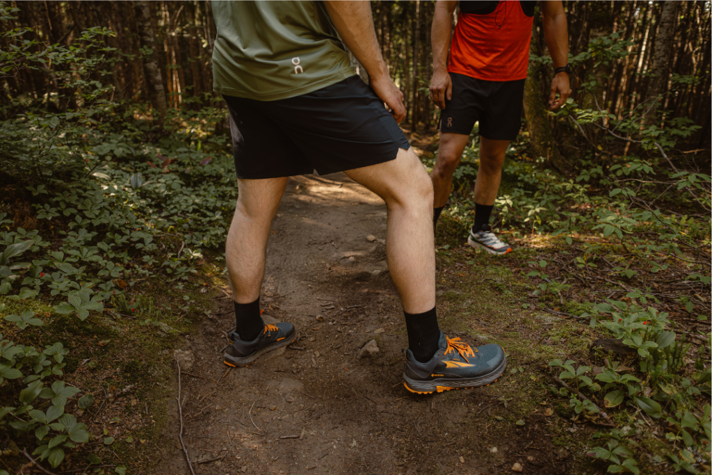 gros plan sur deux personnes portant des chaussures de course en sentier sur un sentier en forêt