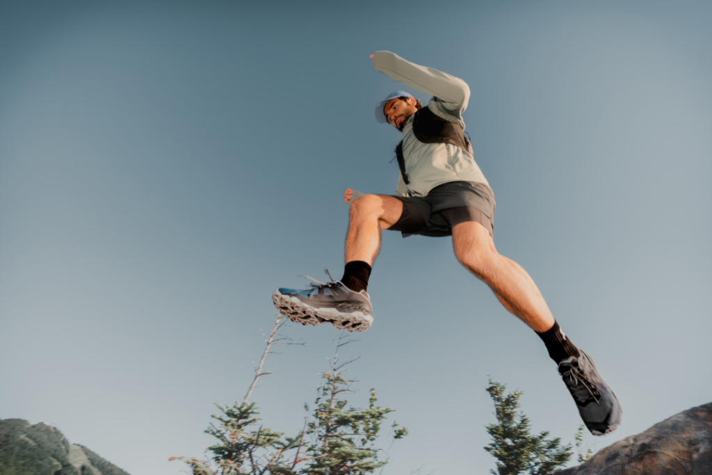 un homme saute sur des rochers avec des chaussures de course en sentier
