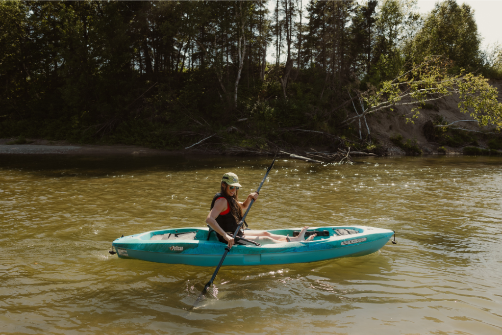 une personne navigue sur un lac calme à bord d'un kayak sit on top (cockpit ouvert)