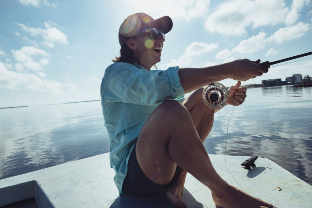 une femme pêche sur un lac par temps ensoleillé en vêtements à protection solaire Columbia PFG