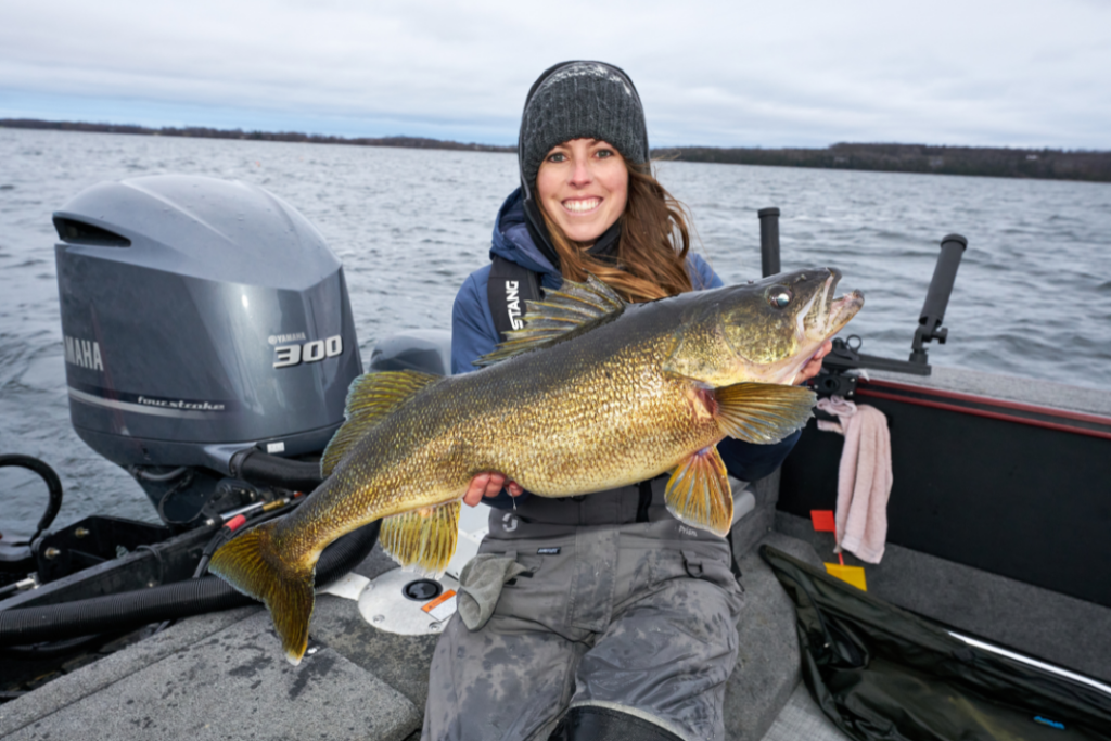 Ashley Rae holding a trophy-size walleye in a boat during fall walleye fishing