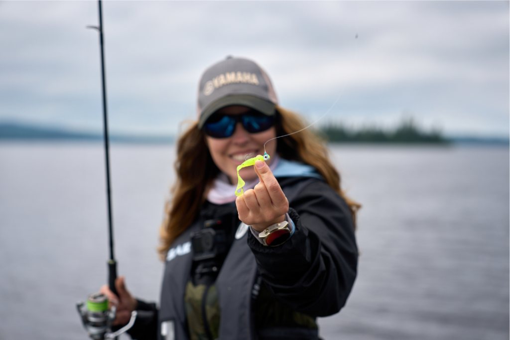 Ashley Rae au bord d’un lac avec une canne à pêche et un leurre souple de couleur vive pour la pêche au doré