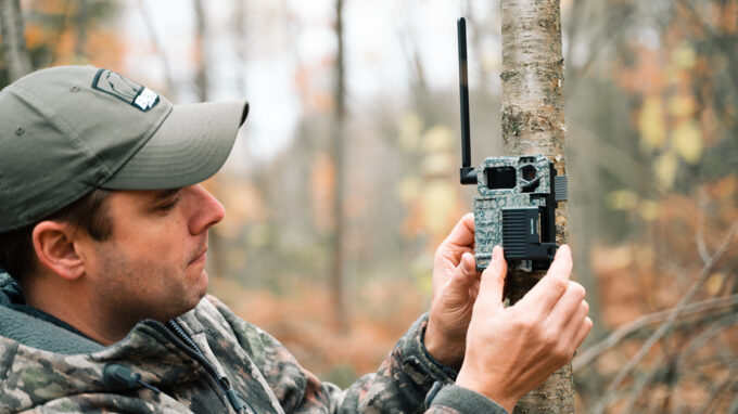 Hunter setting up trail camera to spot white-tailed deer
