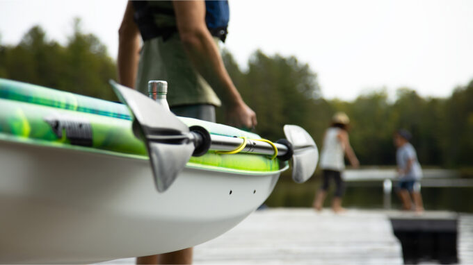 Kayaks - un kayakiste déplace son embarcation sur le bord de l'eau, illustrant le type de kayak idéal pour les rivières à faible courant et les lacs