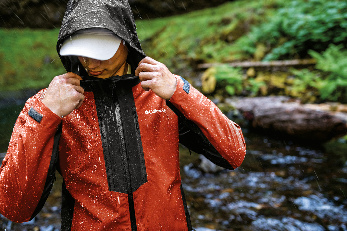 Homme en randonnée sous la pluie portant un manteau technique déperlant Columbia