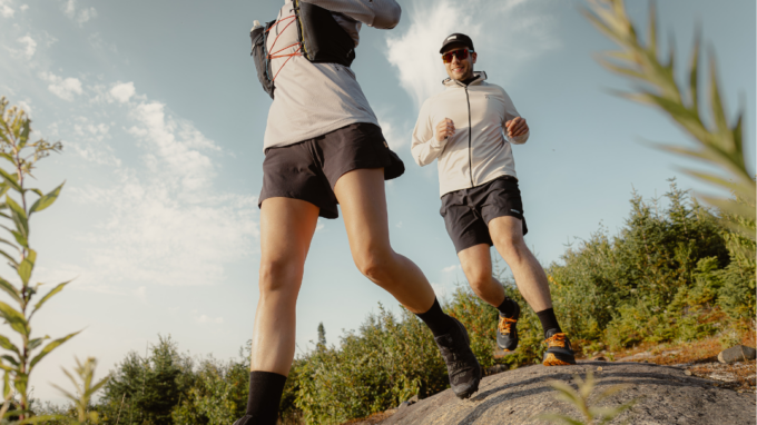 woman and man trail running on rocky terrain in trail running shoes