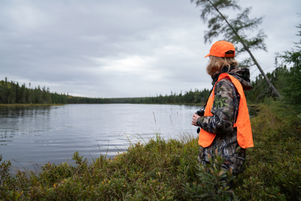 Chasseuse devant un lac dans le calme de la forêt pendant la saison de chasse à l’arc et à l’arbalète